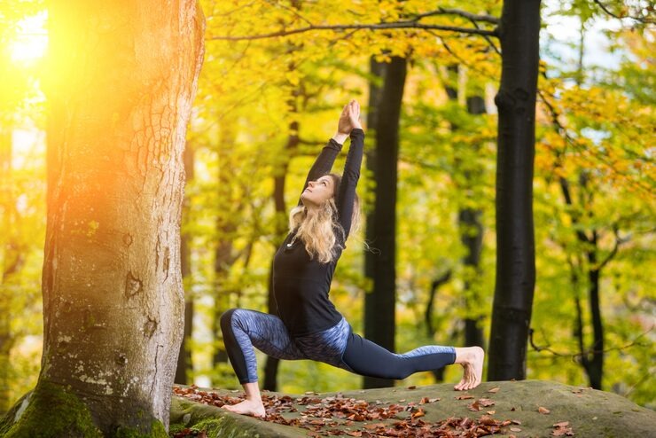 A woman practicing yoga in a serene forest, symbolizing optimal mental health.